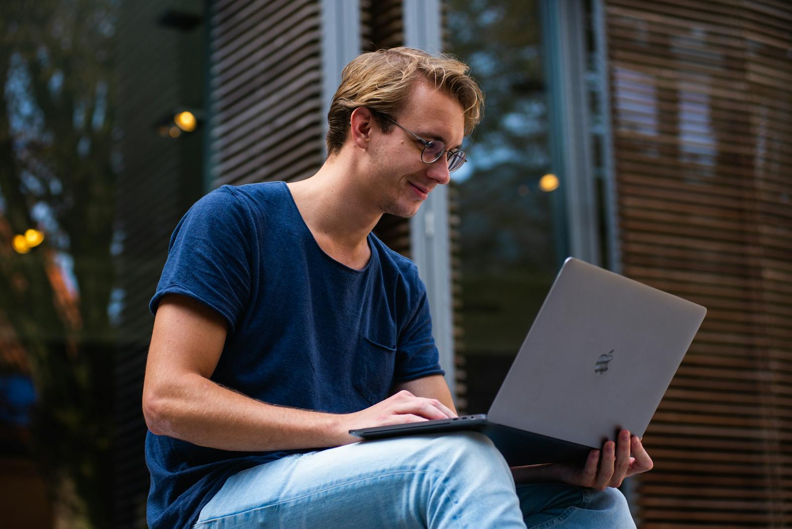 A young man sitting outdoors in Leiden, Netherlands, working on a laptop. business